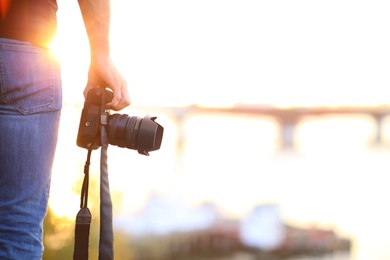 Photo of Photographer with professional camera outdoors on sunny day, closeup