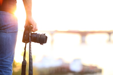 Photographer with professional camera outdoors on sunny day, closeup