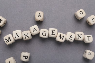 Photo of Word Management made of wooden cubes on grey background, flat lay
