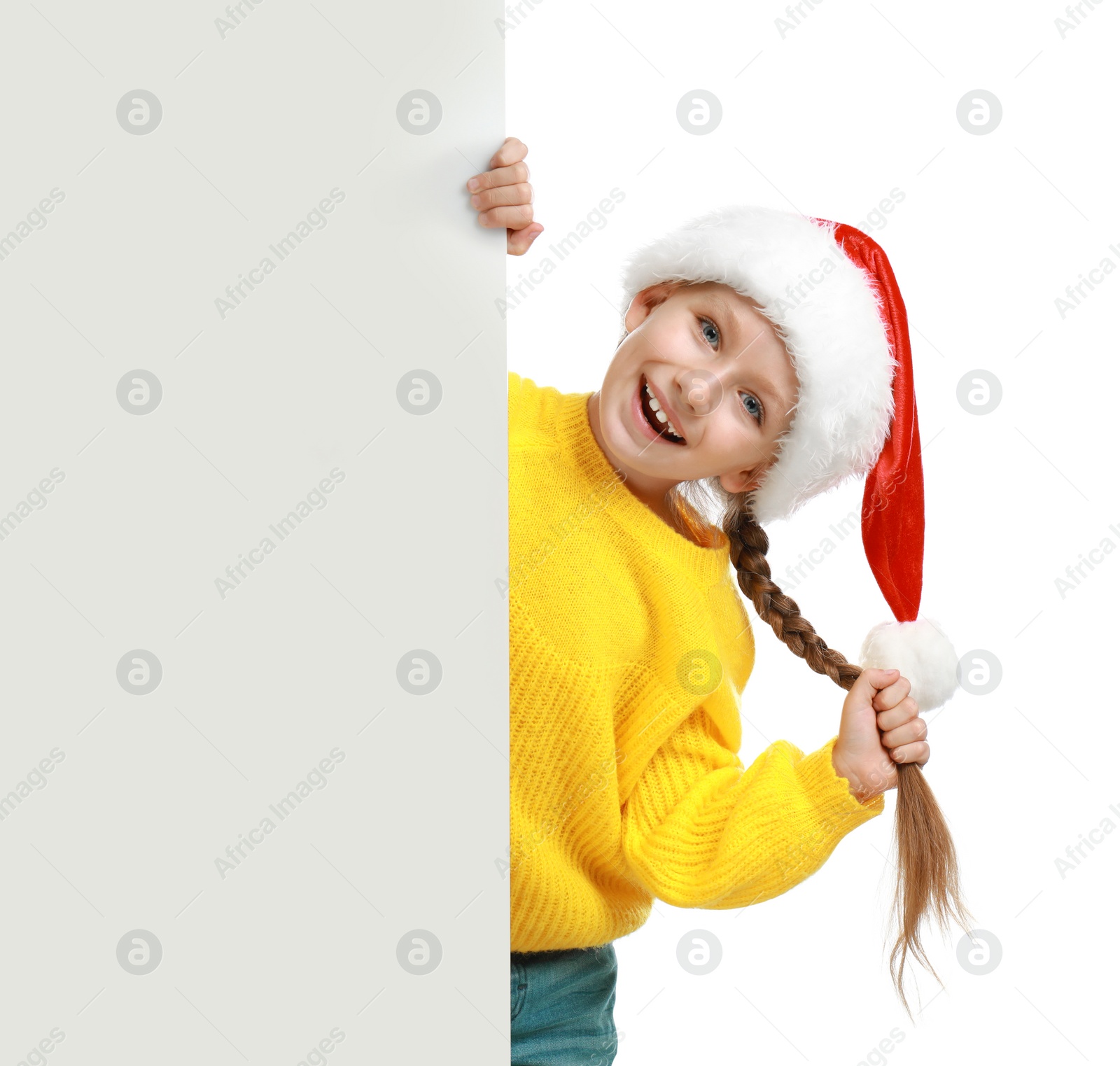 Photo of Happy child in Santa hat peeping out of blank banner on white background. Christmas celebration