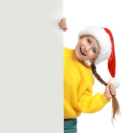 Photo of Happy child in Santa hat peeping out of blank banner on white background. Christmas celebration