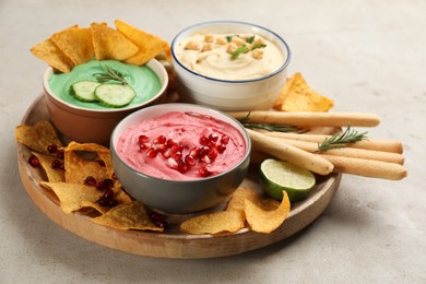 Photo of Different kinds of tasty hummus served with snacks on light table