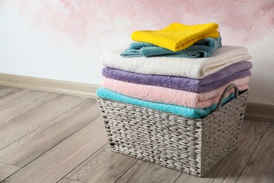 Photo of Basket with clean laundry on wooden floor near pink wall, space for text