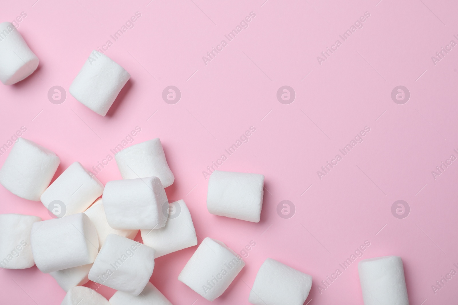 Photo of Delicious puffy marshmallows on pink background, flat lay. Space for text