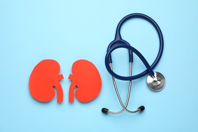 Photo of Paper cutout of kidneys and stethoscope on light blue background, flat lay