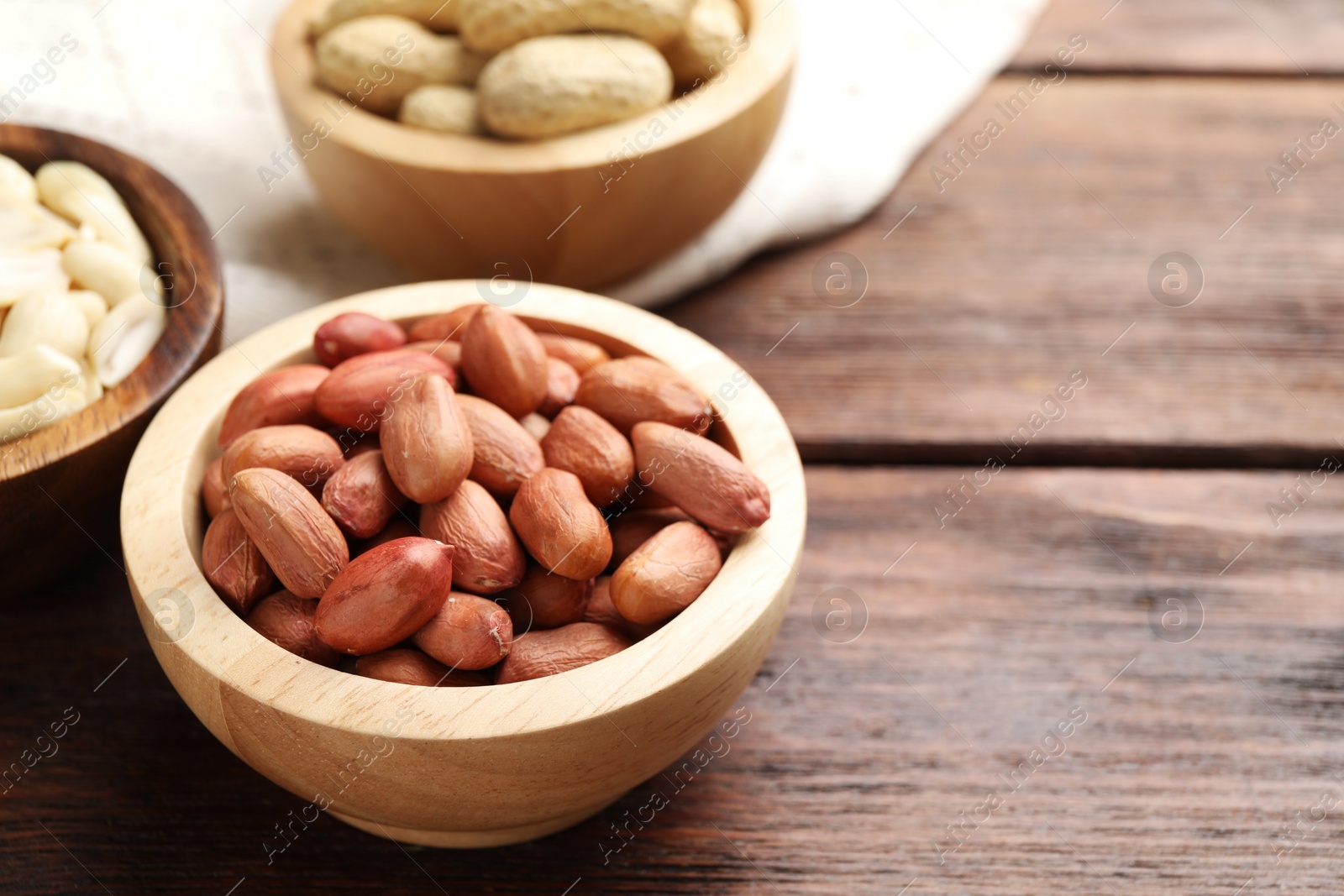 Photo of Fresh peanuts in bowl on wooden table, space for text