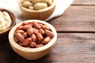 Photo of Fresh peanuts in bowl on wooden table, space for text