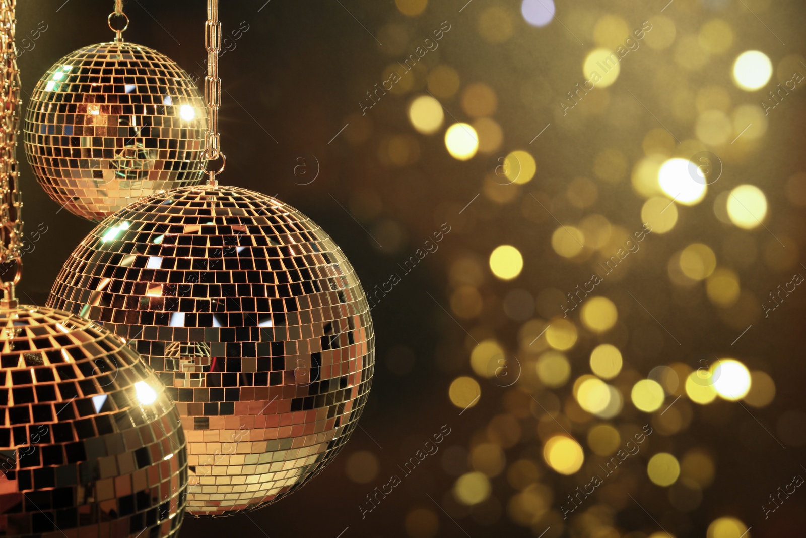 Photo of Shiny disco balls under yellow light, space for text