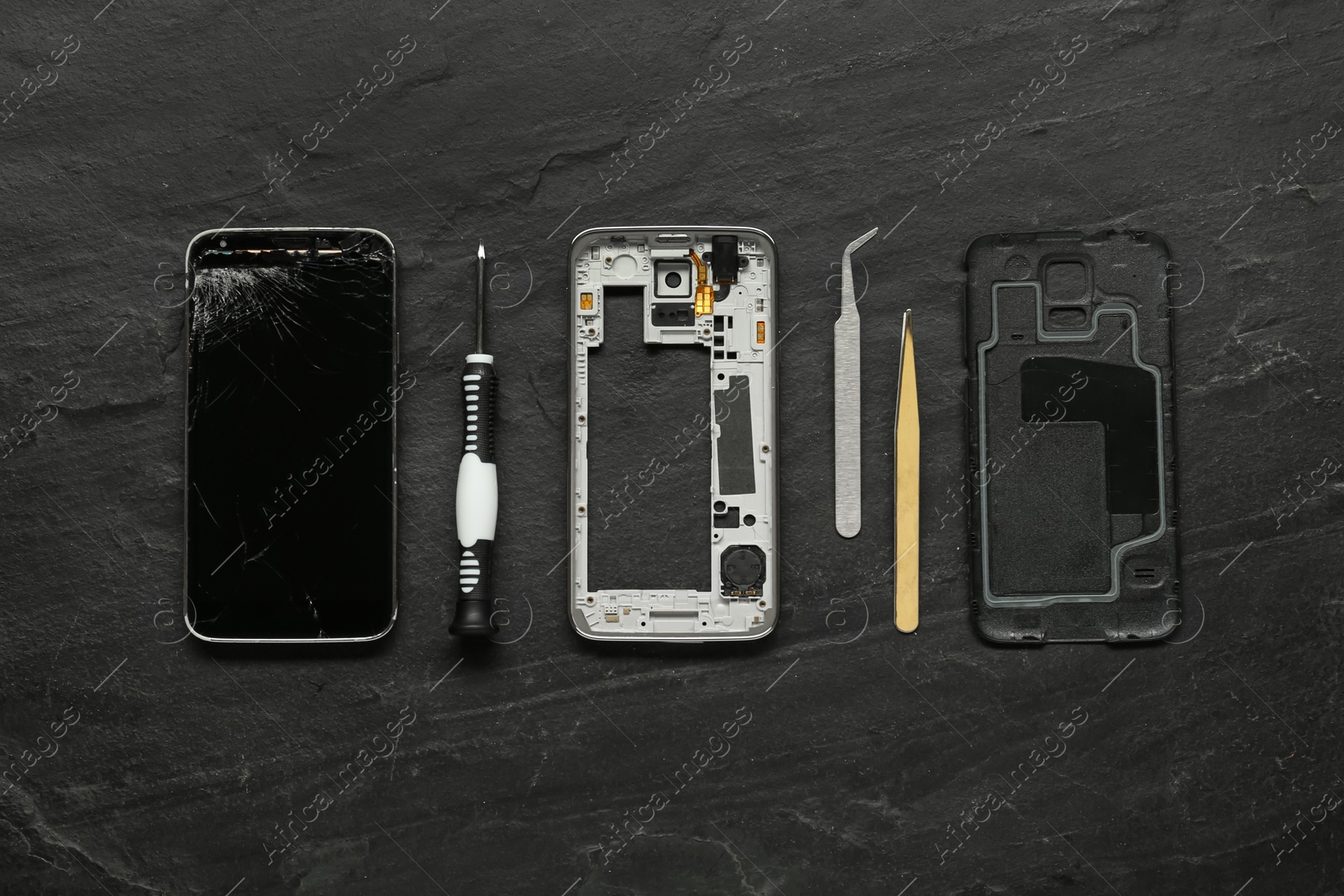 Photo of Damaged smartphone and repair tools on black background, flat lay