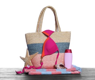 Photo of Stylish bag, starfish and other beach accessories on wooden table against white background