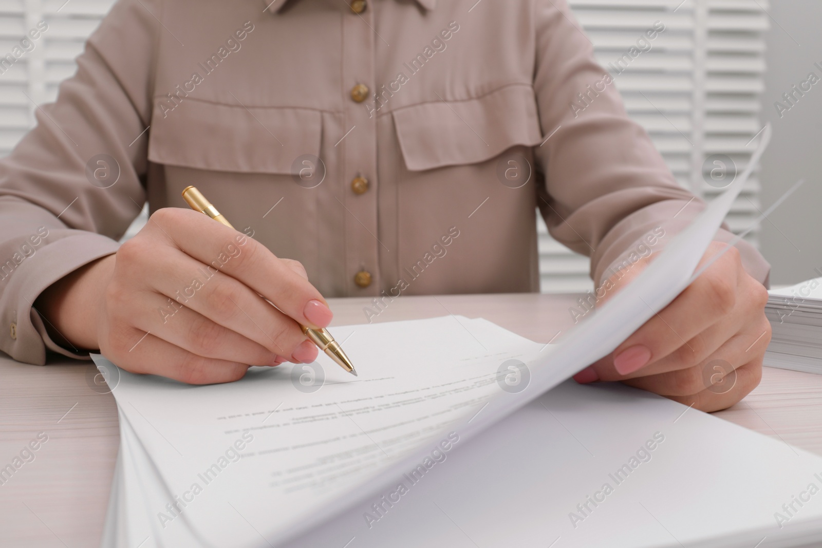 Photo of Woman signing document at table, closeup view