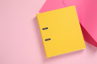 Yellow office folder on pink background, top view. Space for text