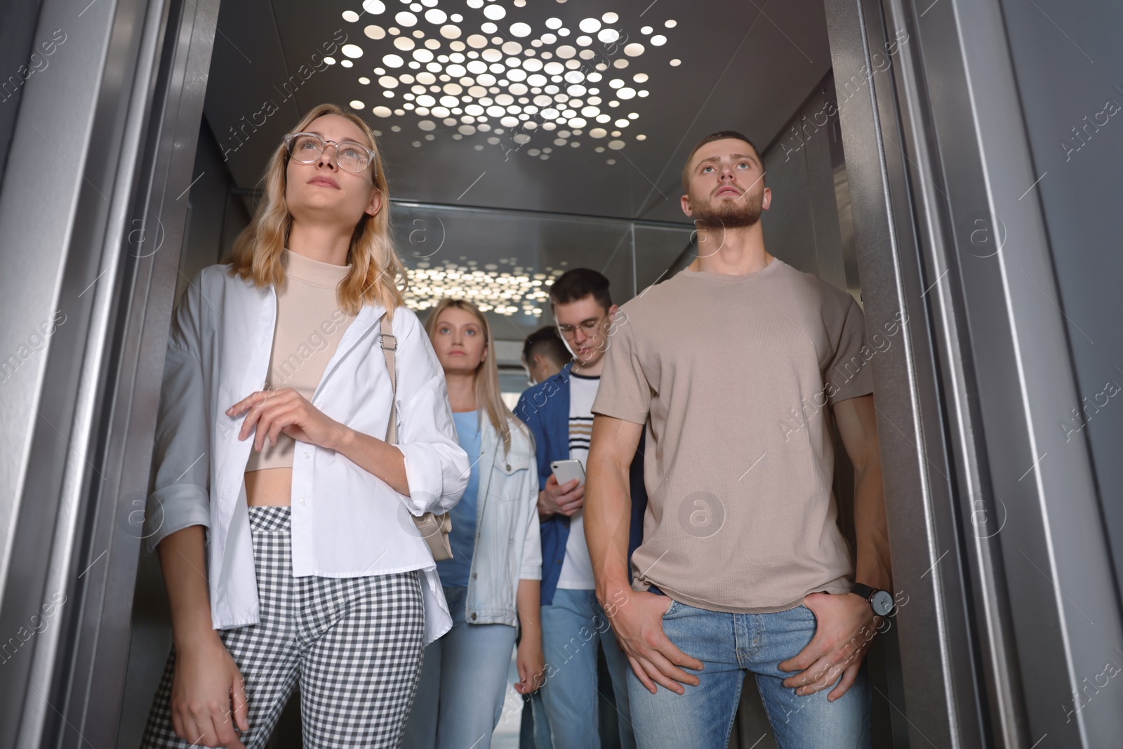 Photo of Group of young people in modern elevator