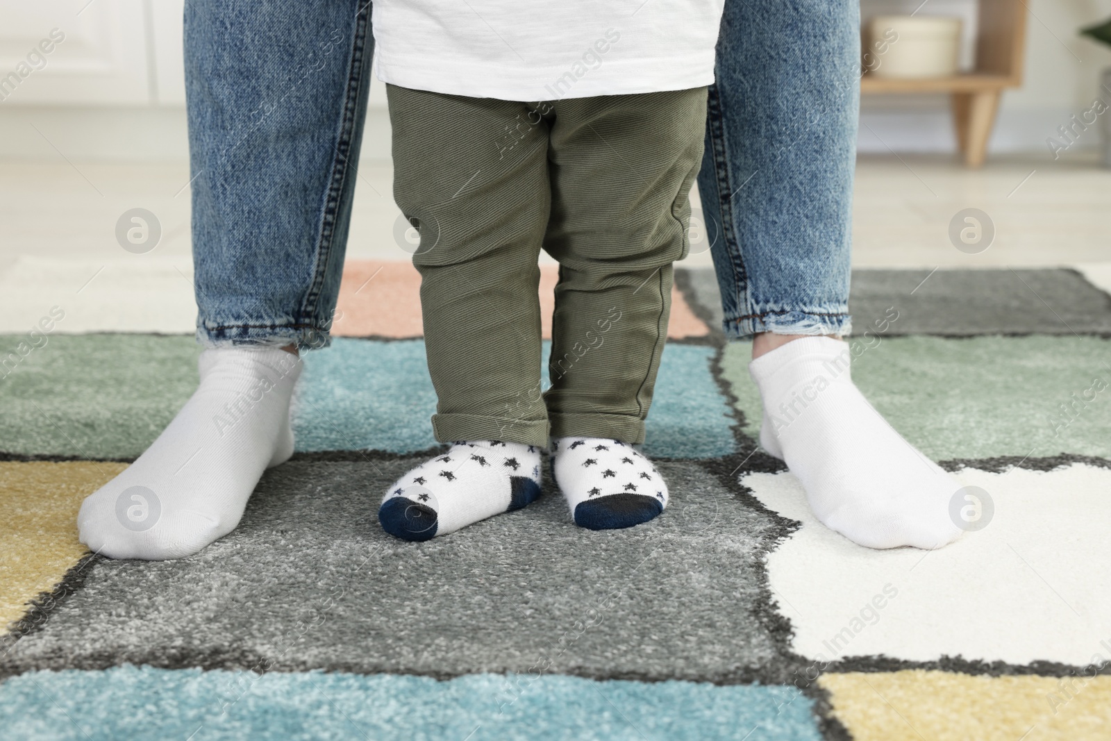 Photo of Mother with her son standing on soft carpet indoors, closeup