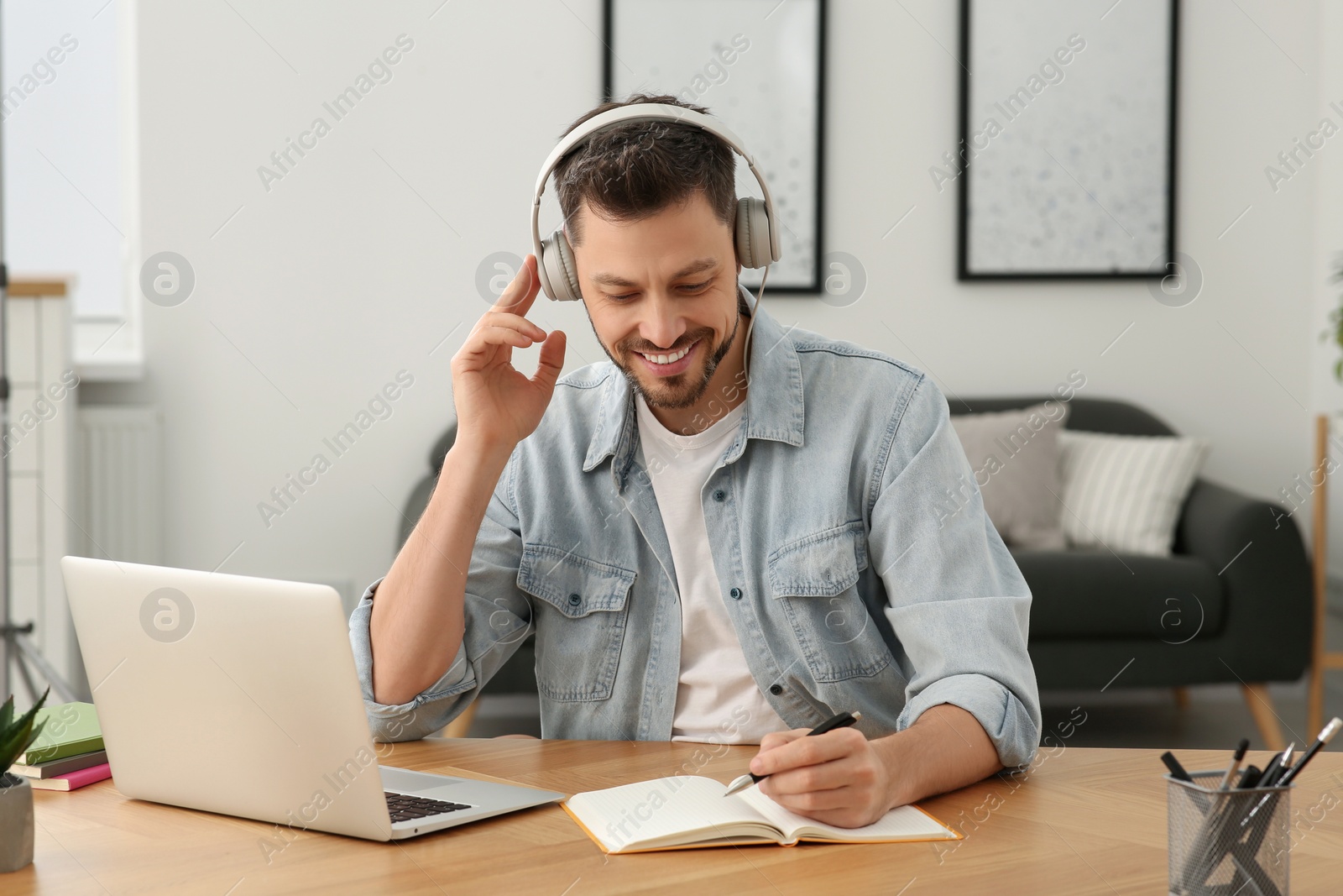 Photo of Man in headphones studying on laptop at home. Online translation course