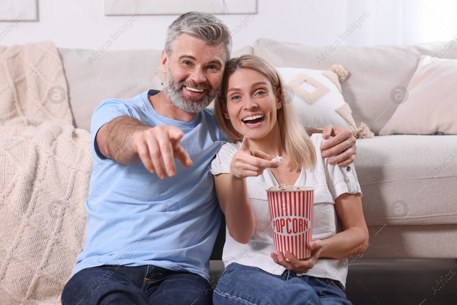 Photo of Happy affectionate couple with popcorn spending time together at home. Romantic date