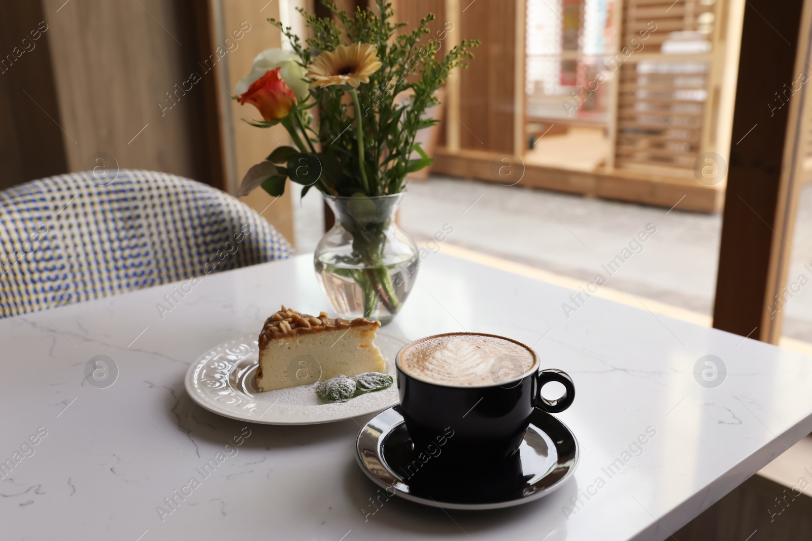 Photo of Cup of fresh coffee and dessert on table in cafeteria