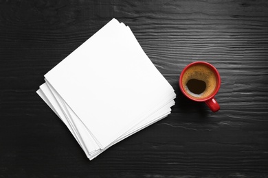 Photo of Blank paper sheets for brochure and cup of coffee on black wooden background, flat lay. Mock up