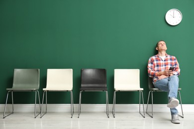 Photo of Man with smartphone waiting for job interview indoors