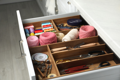 Photo of Sewing accessories in open desk drawer indoors