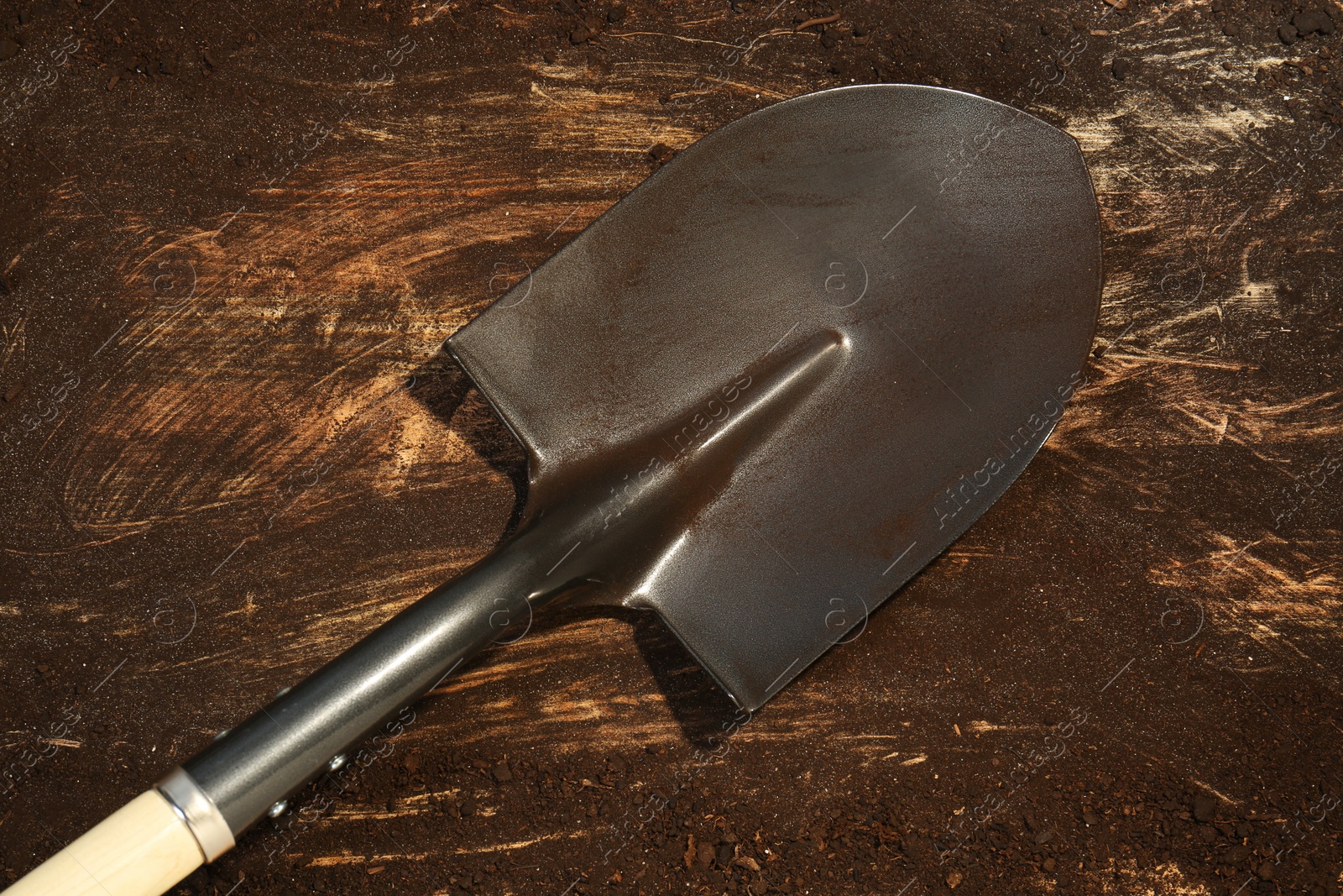 Metal shovel with fertile soil on dirty wooden surface, top view Photo of Metal shovel with fertile soil on dirty wooden surface, top view