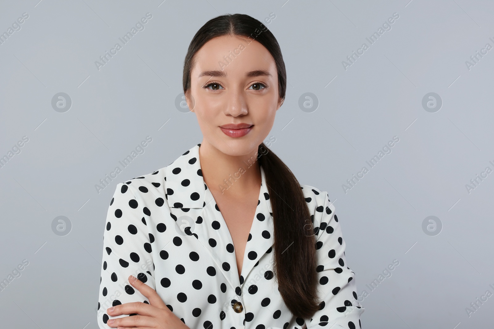 Photo of Portrait of beautiful young woman in polka dot blouse on light grey background