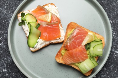 Photo of Tasty toasts with salmon, cream cheese and cucumber on grey table, top view
