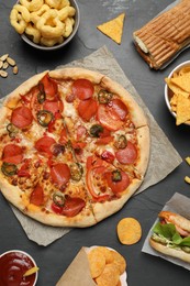 Pizza, onion rings and other fast food on black table, flat lay