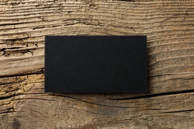 Photo of Empty black business card on wooden background, top view. Mockup for design
