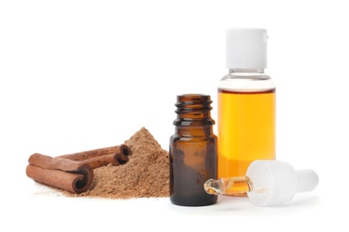 Photo of Bottles with cinnamon oil, powder and sticks on white background