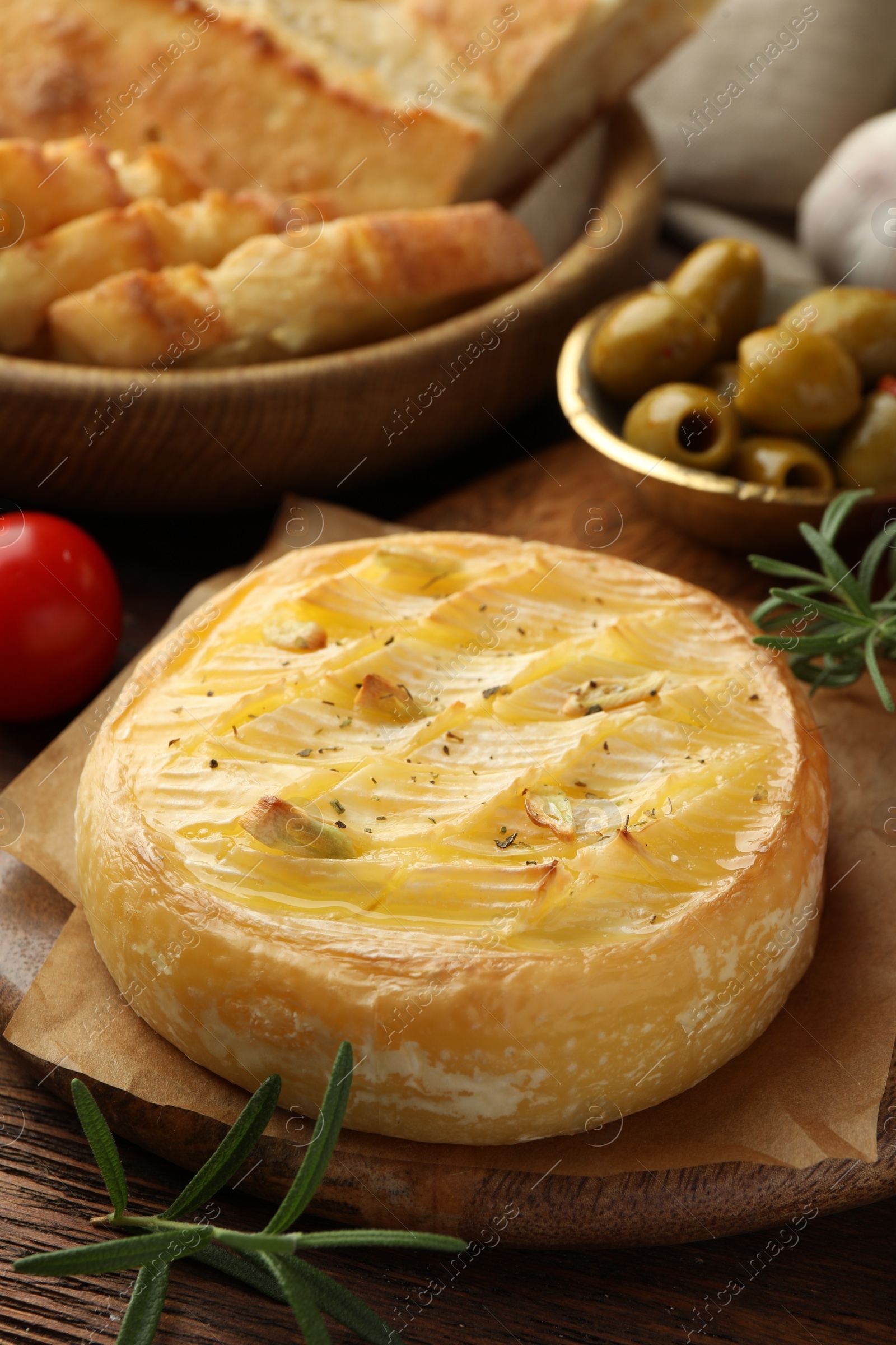 Photo of Tasty baked brie cheese served on wooden table, closeup