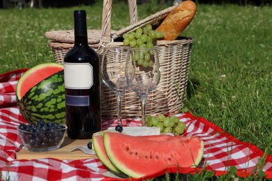 Photo of Picnic blanket with delicious food and wine outdoors on summer day