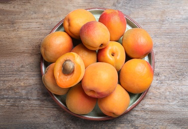 Photo of Delicious fresh ripe apricots on wooden table, top view