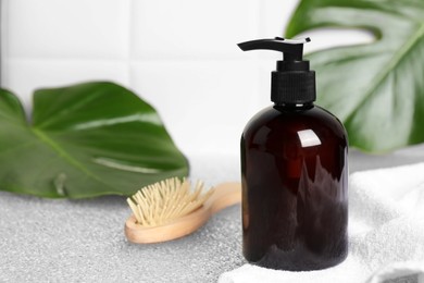 Photo of Shampoo bottle, brush, towel and green leaf on light table, space for text