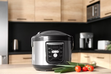 Photo of Modern multi cooker and ingredients on table in kitchen