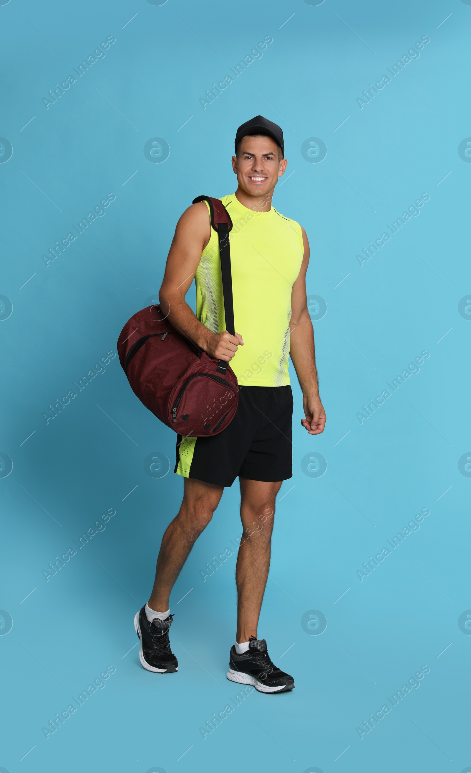 Photo of Handsome man with sports bag on light blue background