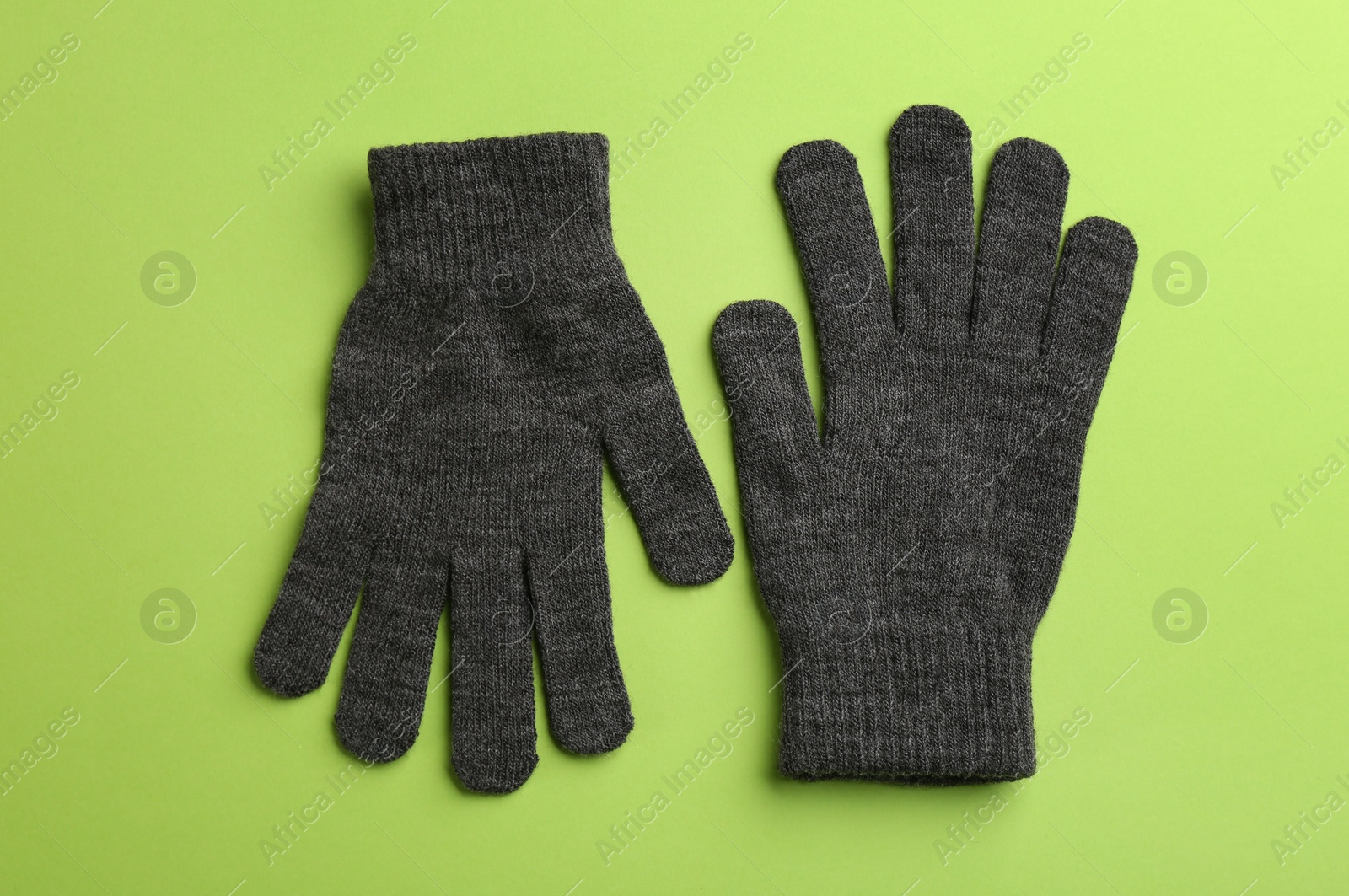 Photo of Pair of stylish woolen gloves on green background, flat lay