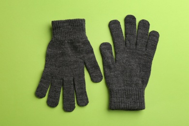 Pair of stylish woolen gloves on green background, flat lay
