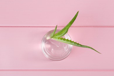 Photo of Jar of natural gel and aloe vera leaves on pink wooden table, top view