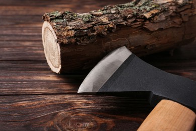 Photo of Metal ax and wooden log on table, closeup