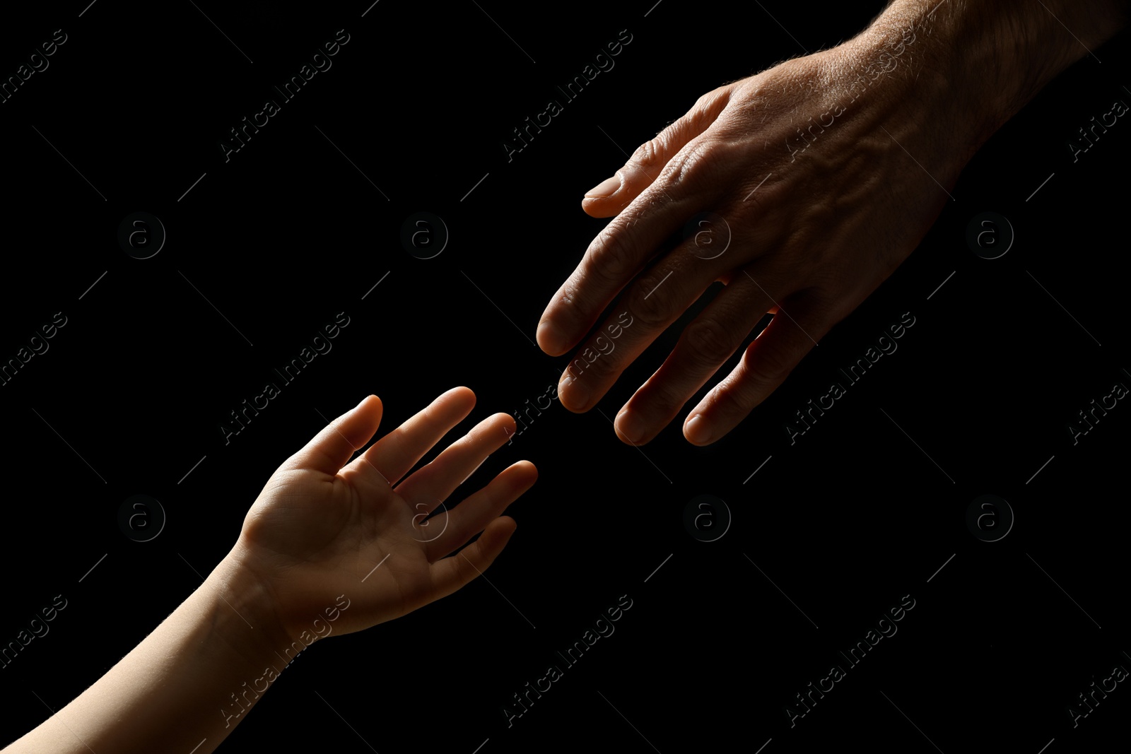Photo of Man with child on black background, closeup of hands