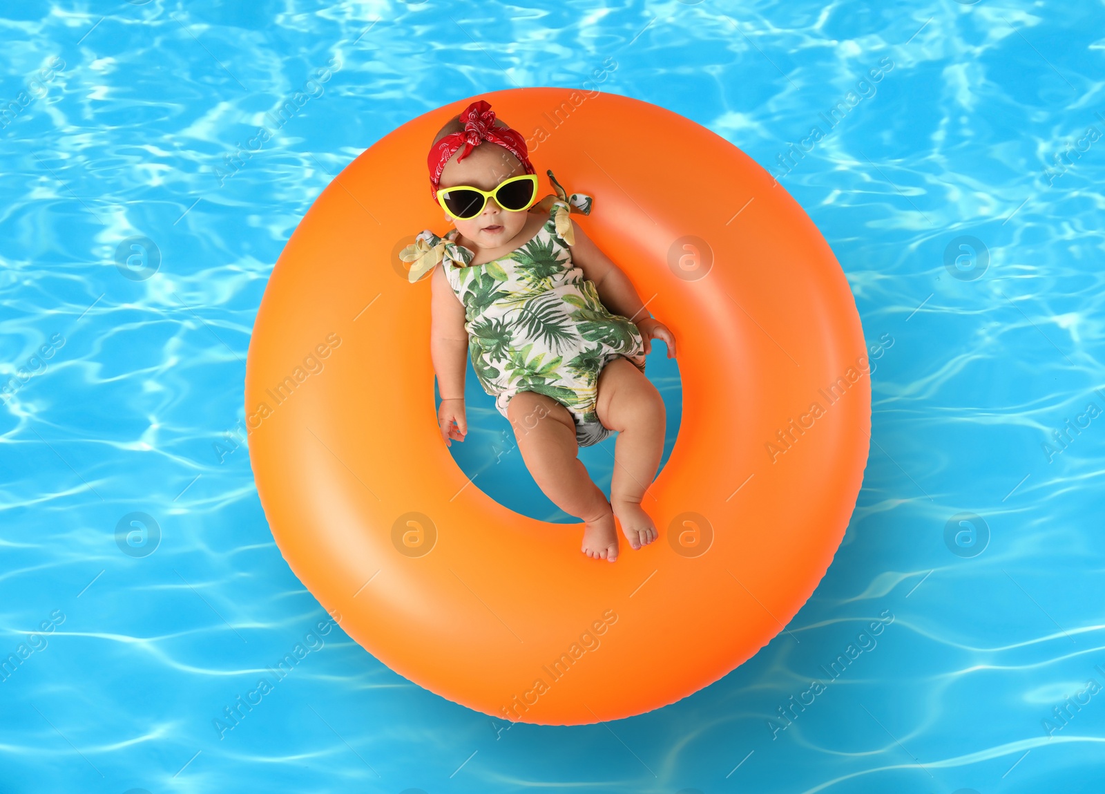 Image of Cute little baby with inflatable ring in swimming pool, top view