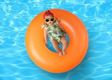 Cute little baby with inflatable ring in swimming pool, top view