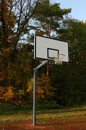 Basketball backboard with net on court near trees