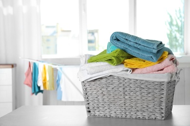Photo of Basket with clean laundry on table at home, space for text