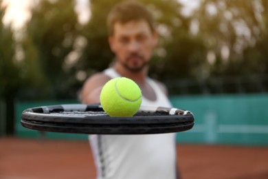 Photo of Handsome man playing tennis outdoors, focus on racket