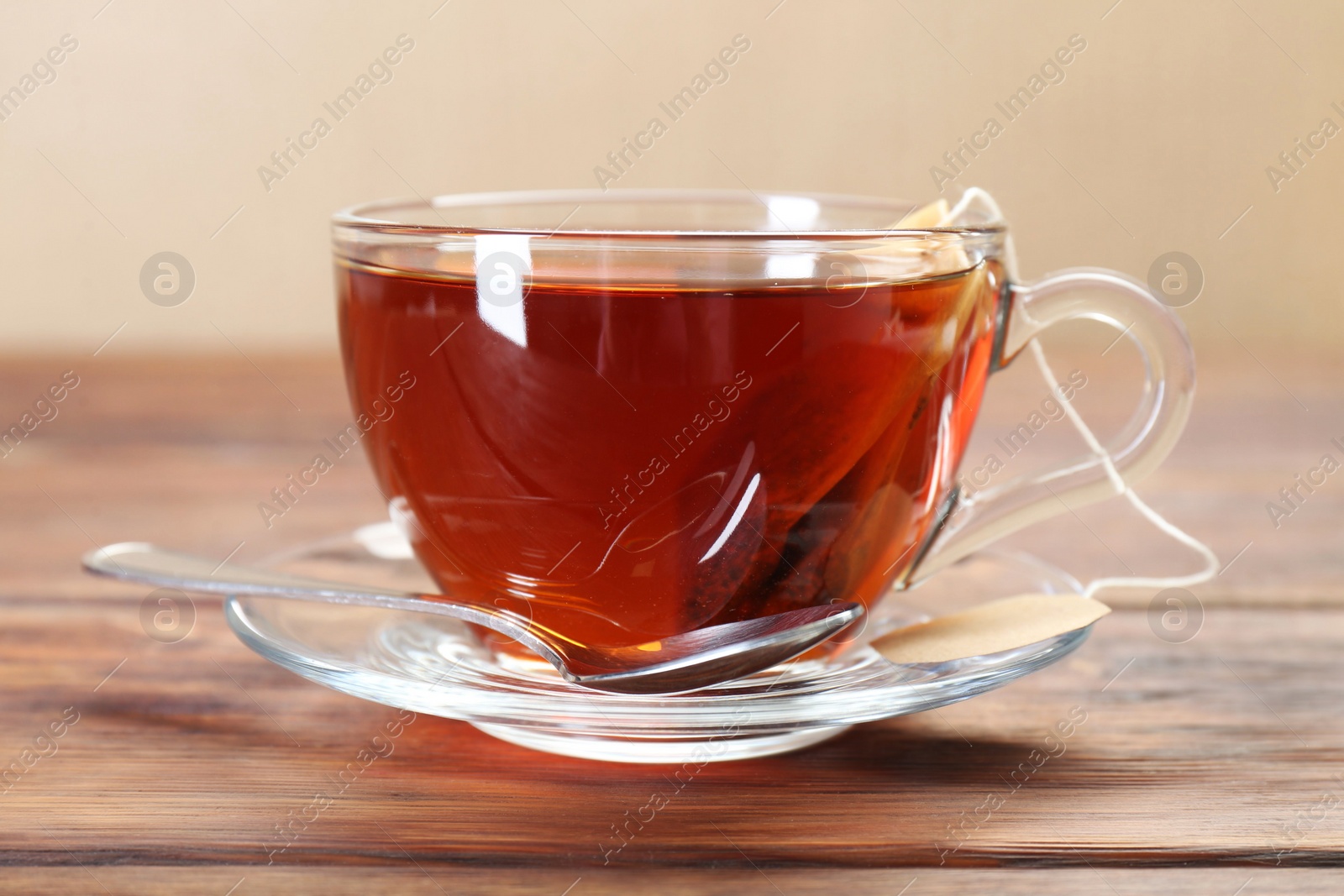 Photo of Brewing aromatic tea. Cup with teabag and spoon on wooden table