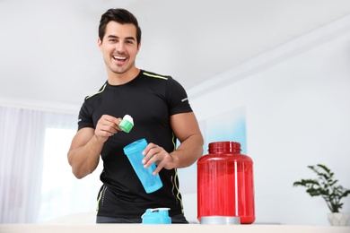 Photo of Young athletic man preparing protein shake at home