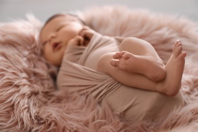 Photo of Cute newborn baby sleeping on fuzzy blanket, focus on legs