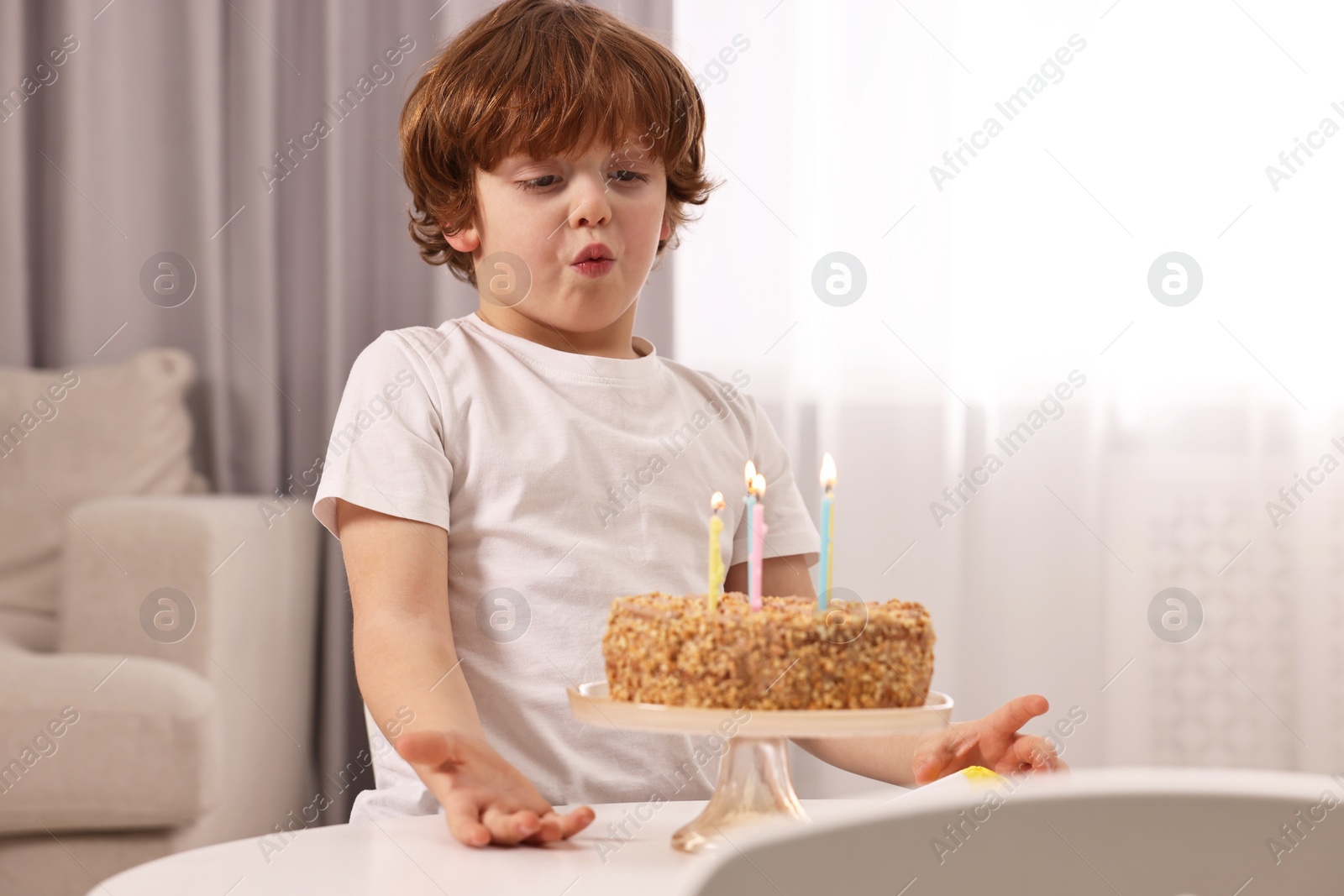 Photo of Cute boy with birthday cake at table indoors